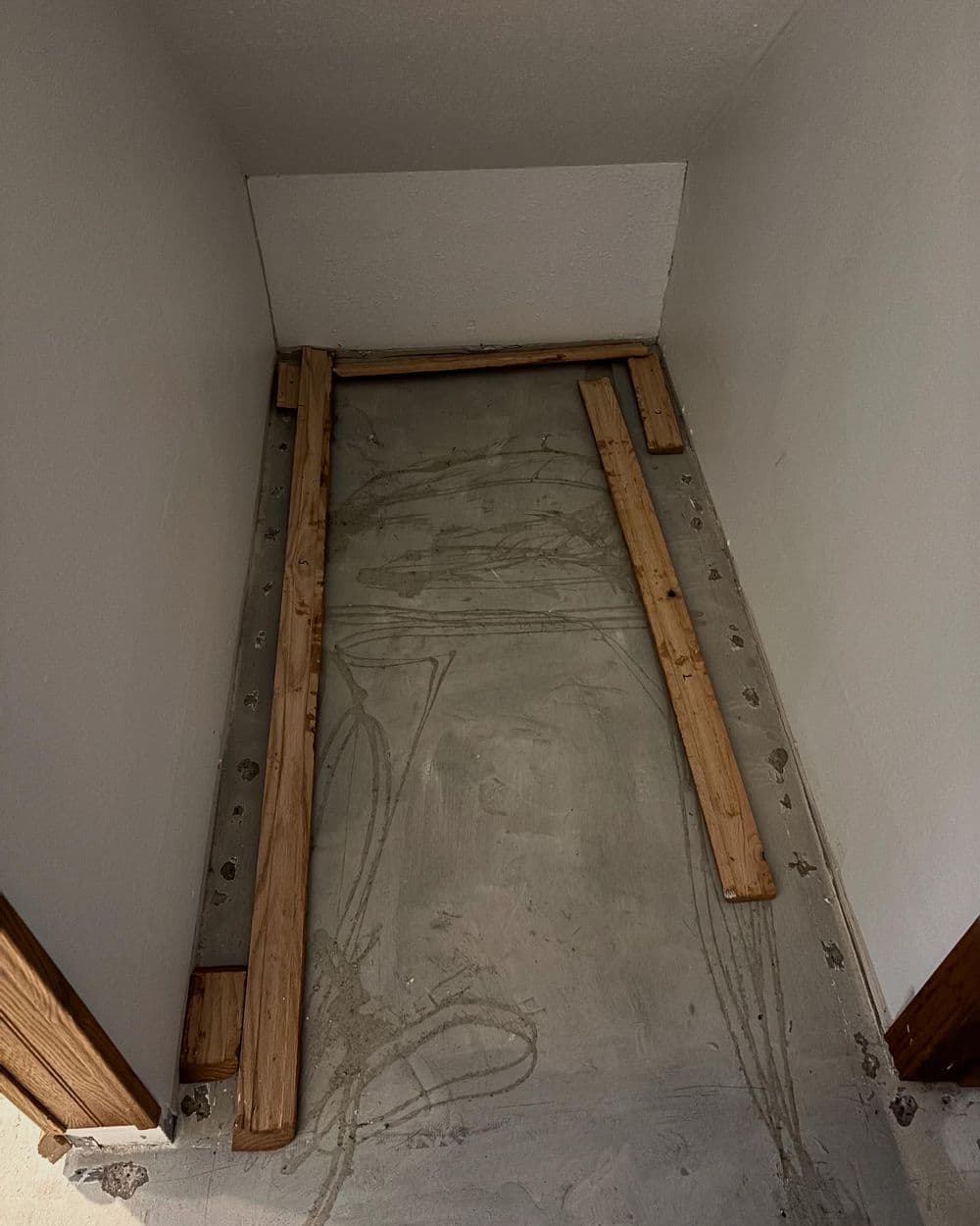 Empty room with wooden planks laid on a concrete floor, ready for flooring installation.