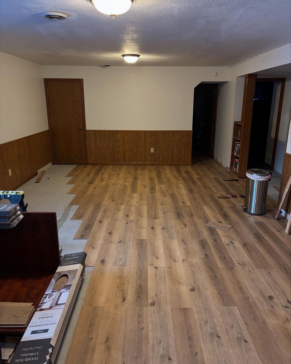 Renovated interior room with wooden flooring, wainscoting, and open space for furniture.