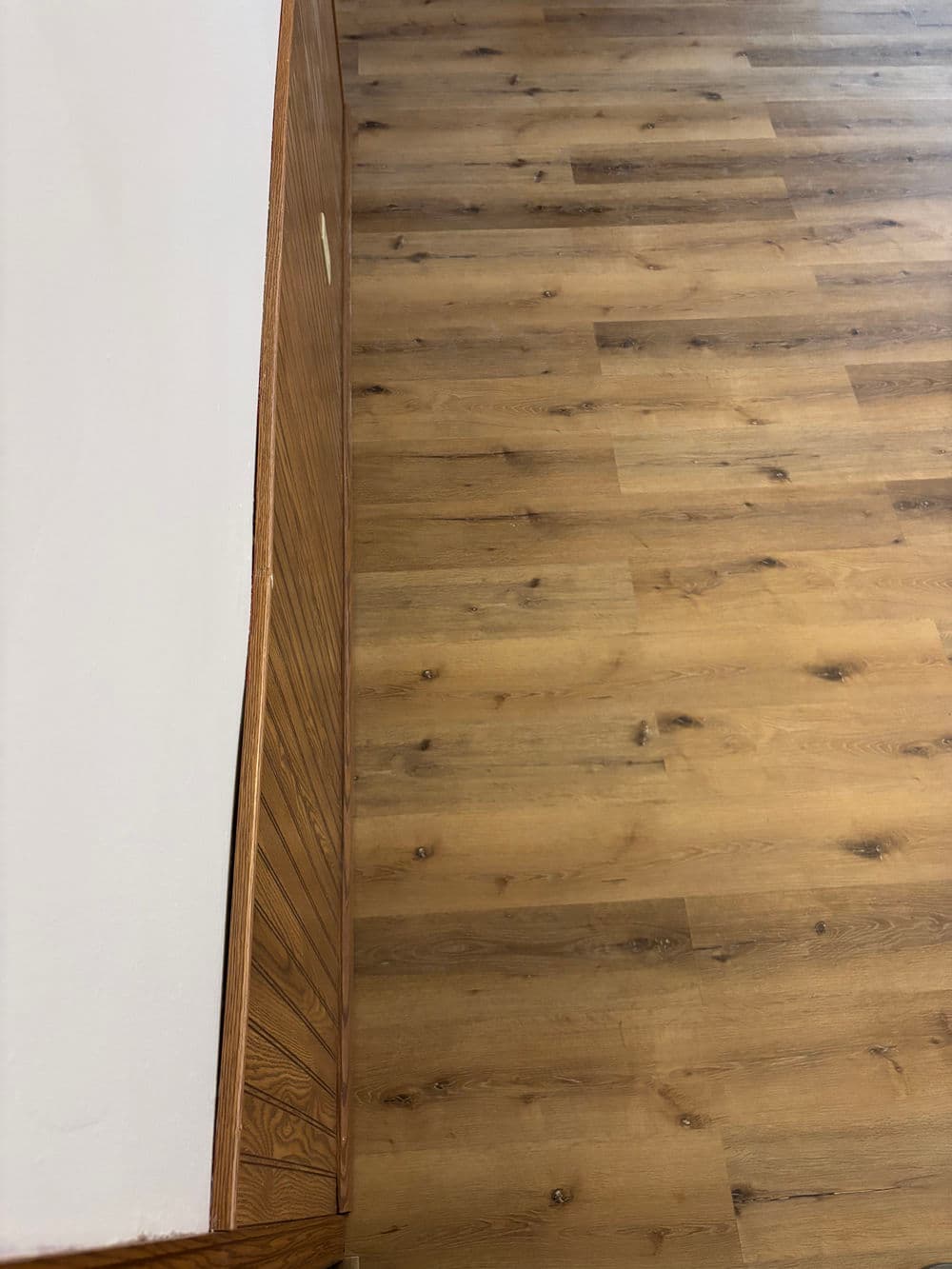Wooden floor with a textured grain pattern and a corner of a wooden cabinet.