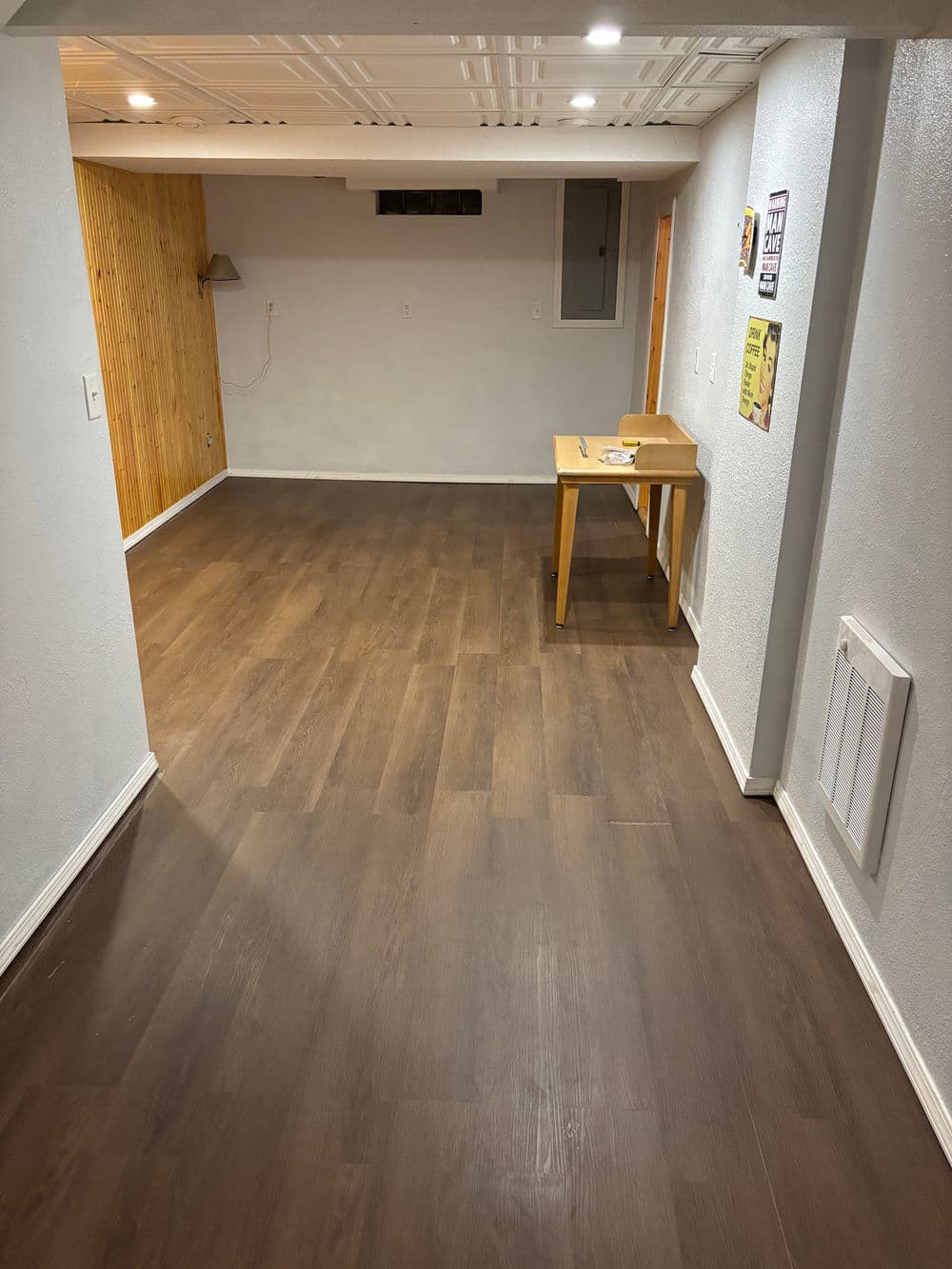 Spacious empty basement interior with wooden flooring and natural light from a window.