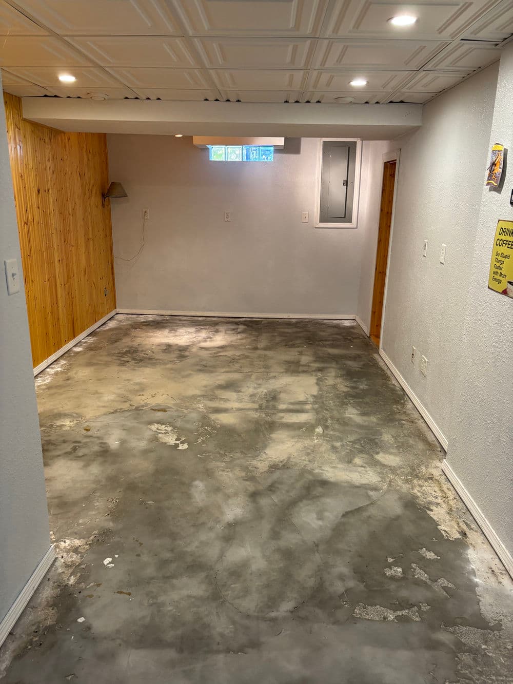 Renovated basement with concrete floor, wall paneling, and natural light from small window.
