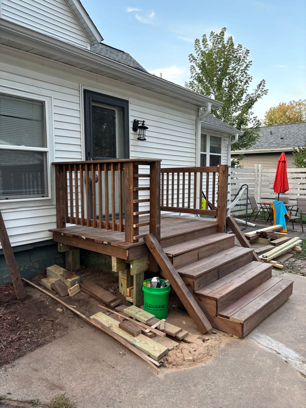 New wooden stairs leading to a home's back porch, featuring sturdy railings and construction materials.