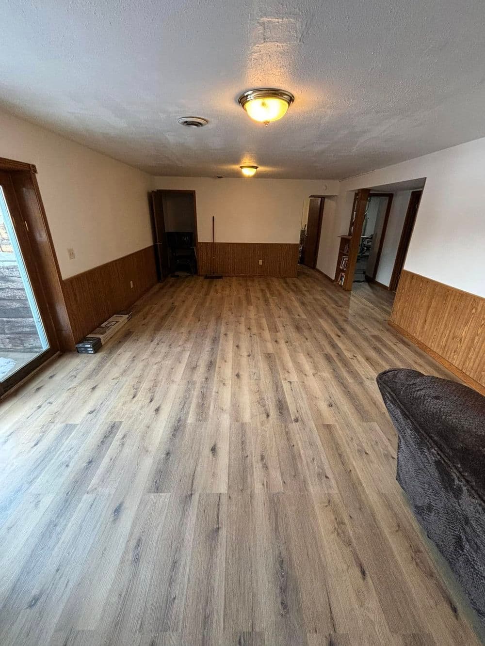 Spacious interior living room with wood paneling and new laminate flooring.